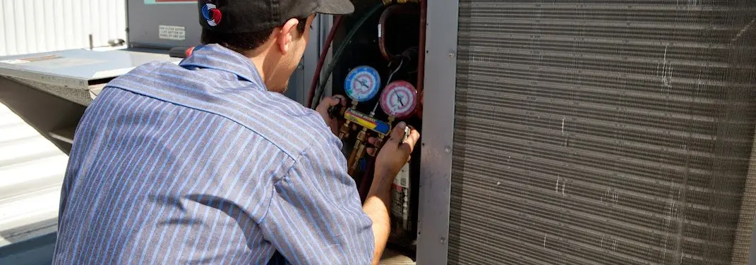 HVAC technician servicing a condenser unit in Mundy