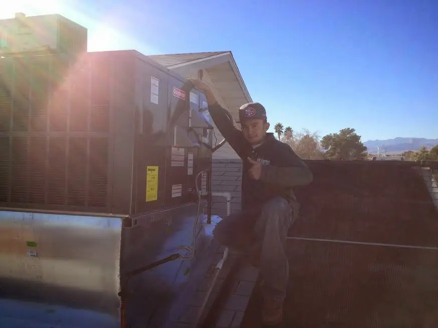 HVAC technician performing AC Tune-Up on a rooftop unit in Mundy